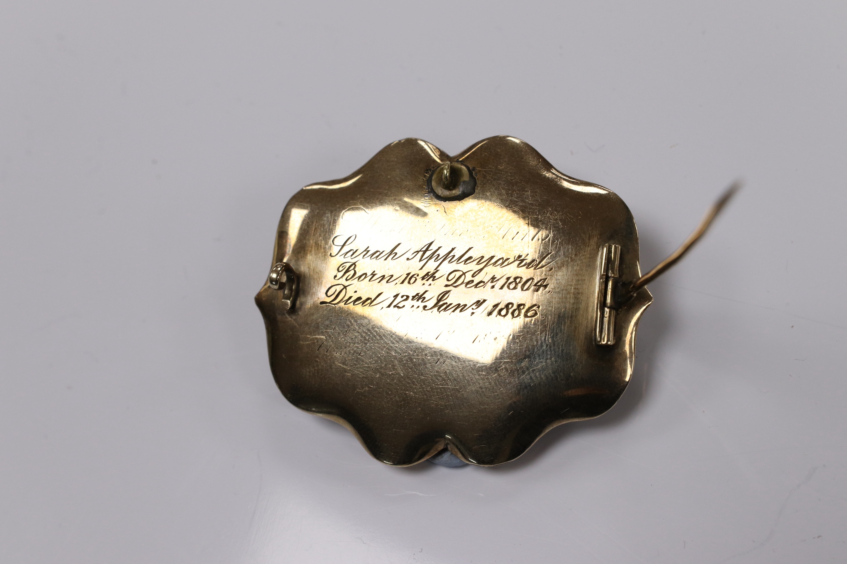 A late Victorian yellow metal, black enamel and split pearl set mourning brooch, with engraved inscription 'Sarah Appleyard, born 16th December 1804, died 12th Jan 1886', 46mm, with hair below a glazed panel. Condition -